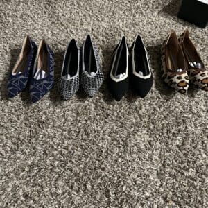 Four pairs of women's dress shoes neatly lined up on carpet.
